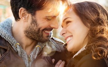 Pareja sonriendo, mirándose a los ojos.