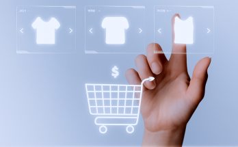 Prendas de ropa, una mano con el dedo índice seleccionando una de ellas y un carrito de la compra en el centro de la imagen.